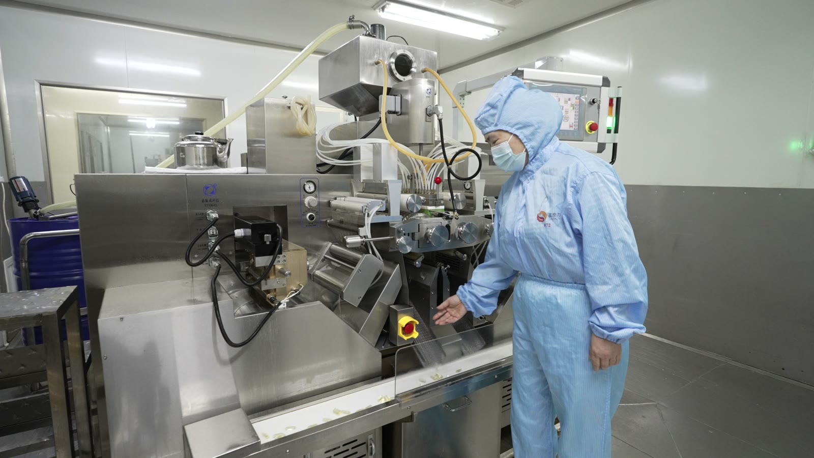 Operator working beside capsule production equipment