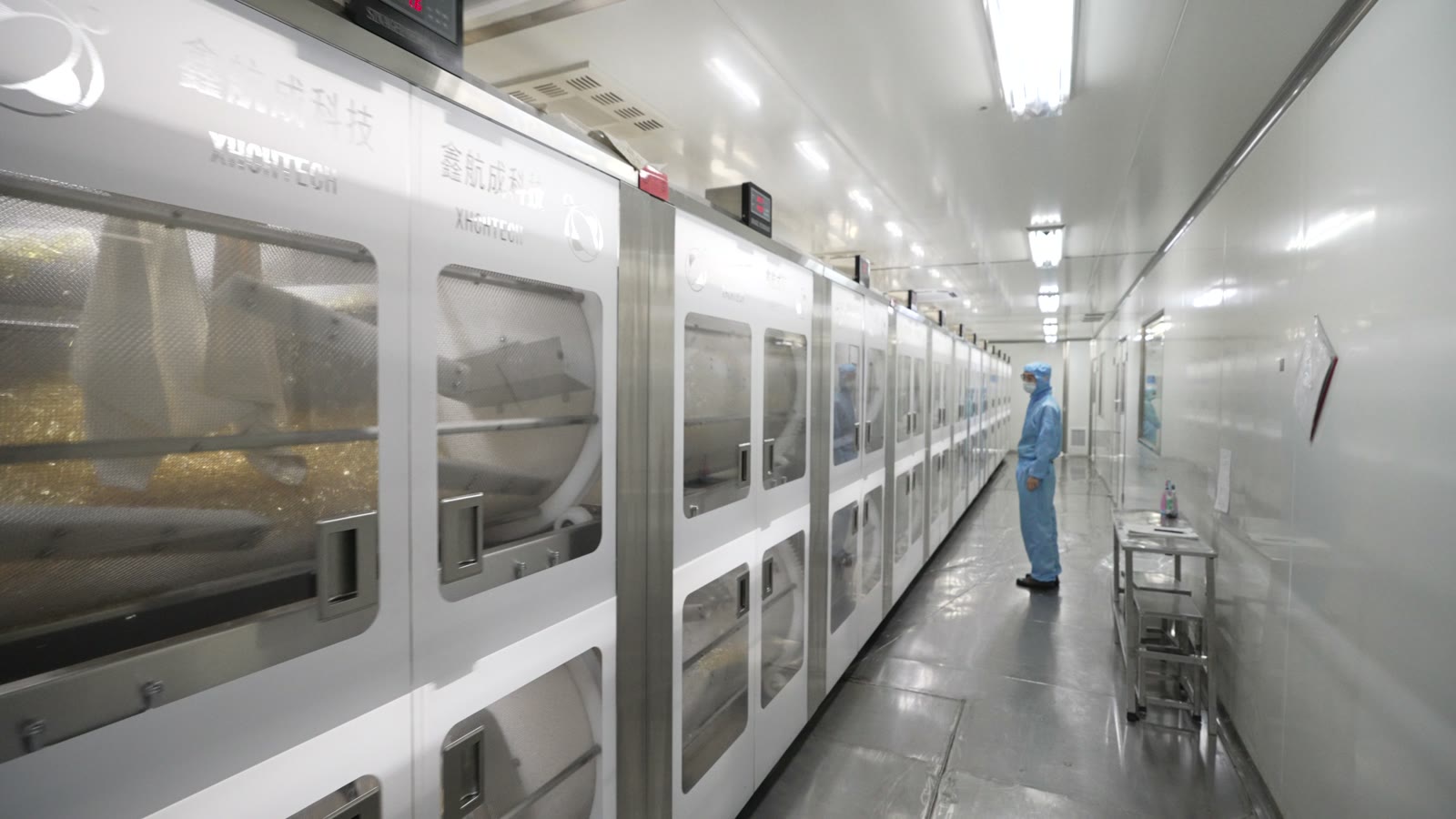 Long rows of enclosed production equipment in a manufacturing corridor